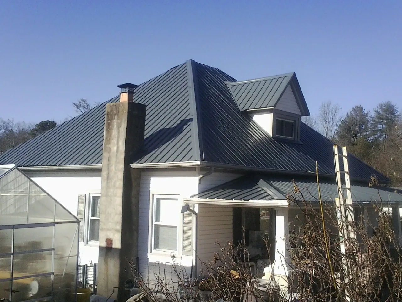 Dark blue standing seam metal roof on a white farmhouse with dormer — Slate & Tile Roof Repair by Roofing Brothers in Ducktown