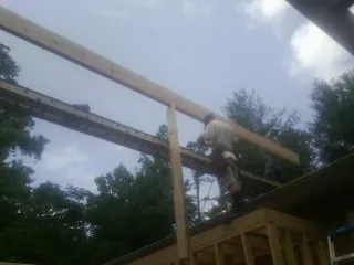 Carpenter setting a ridge beam over a new addition frame — Ice Dam Removal by Roofing Brothers in Ducktown
