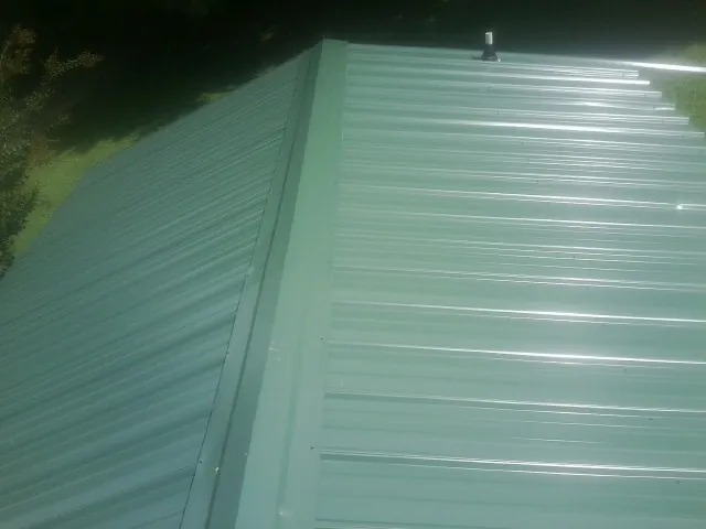 New green metal panels meeting at the ridge of a roof — Flat Roof Repair work by our crew in Ducktown