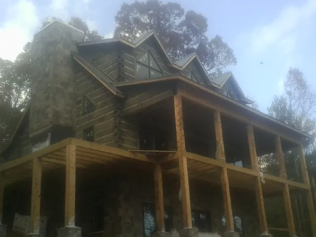 Stone chimney and dormers on a large log home with a timber porch in Ducktown