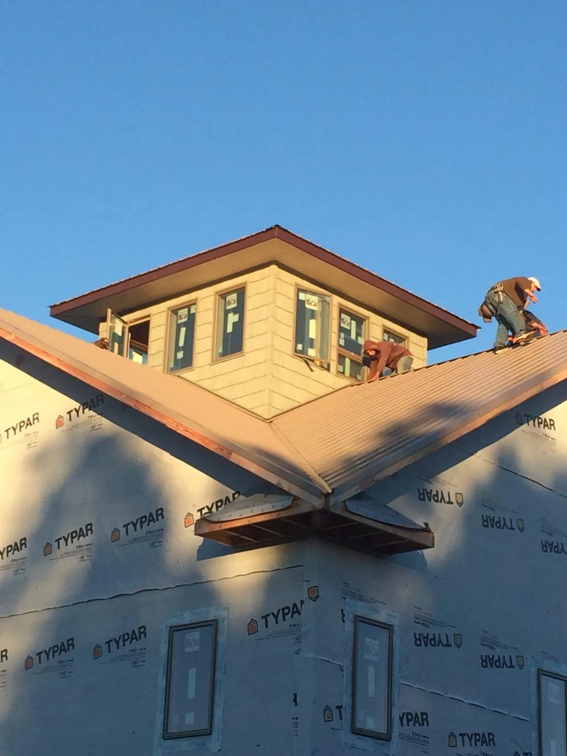 Roofers working around a rooftop cupola on a new metal roof at sunset — Roof Waterproofing in Ducktown by Roofing Brothers